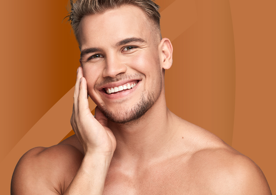 Lächelnder junger Mann mit trainierter Statur, der sein Gesicht mit einer Hand berührt – Symbolbild für plastische Chirurgie für Männer in Frankfurt