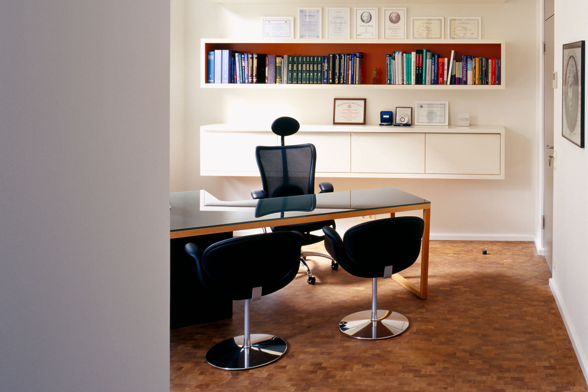 Beratungszimmer der Praxis Aesthetik von Heimburg in Frankfurt mit Schreibtisch, Stühlen und Bücherregal